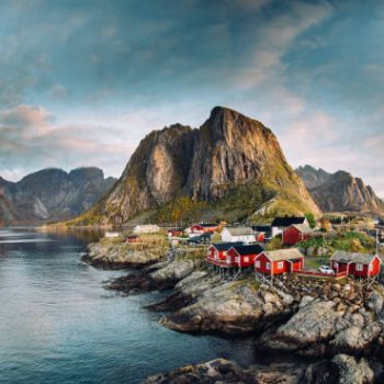Norwegian fishing village at the Lofoten Islands in Norway. Dramatic sunset clouds moving over steep mountain peaks