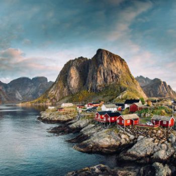Norwegian fishing village at the Lofoten Islands in Norway. Dramatic sunset clouds moving over steep mountain peaks